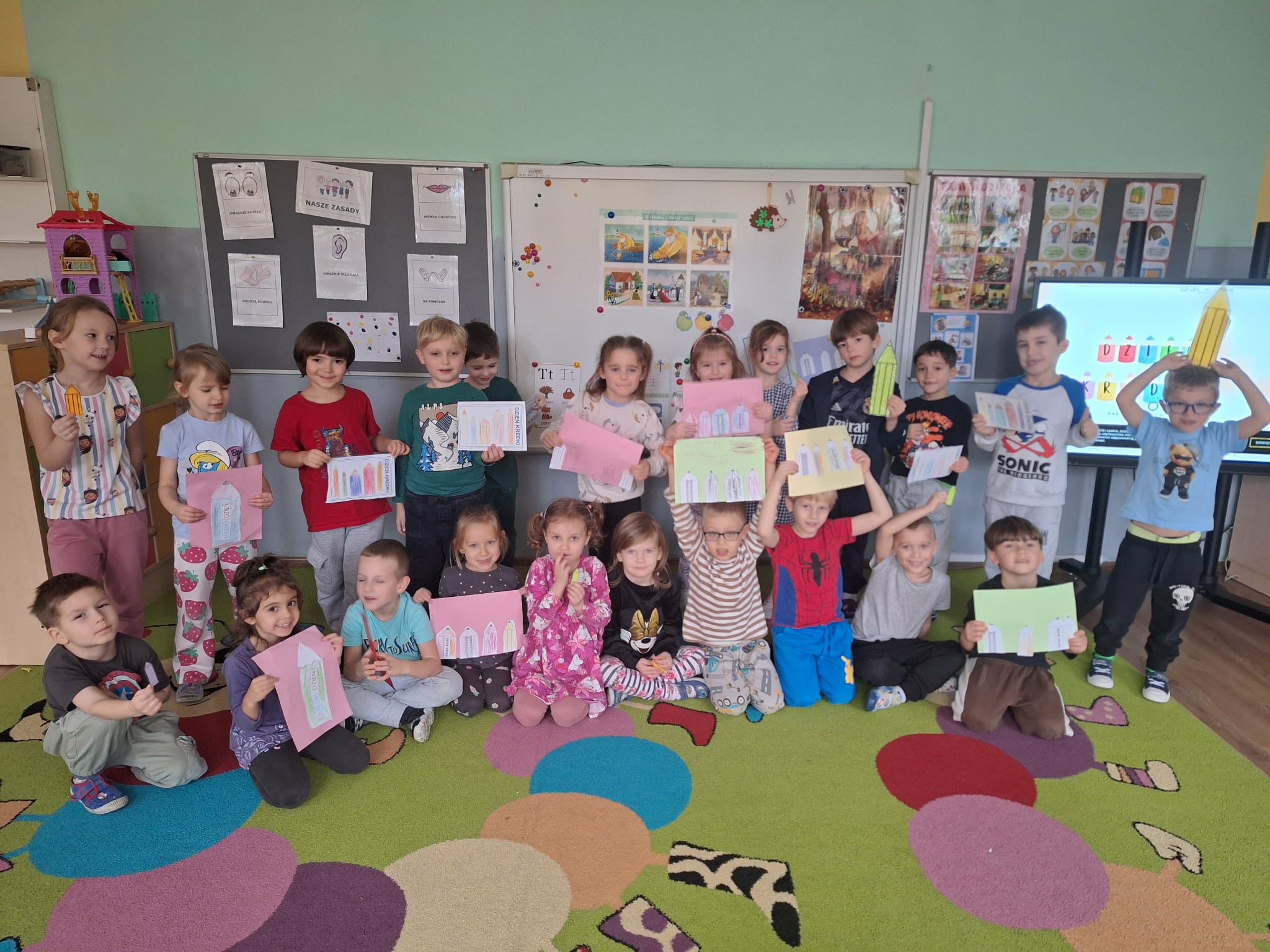 dzieci stojące z pracami plastycznymi 