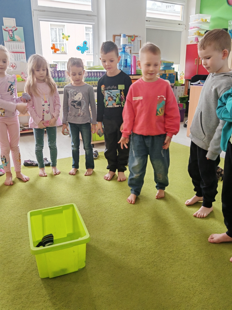 Dzień kolorowej skarpetki - dzieci kolejno rzucają kulkami do pudełka.