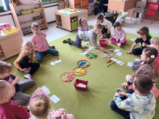 Dzień matematyki - dzieci siedzą w kole na dywanie, Szymon wykonuje zadanie. 