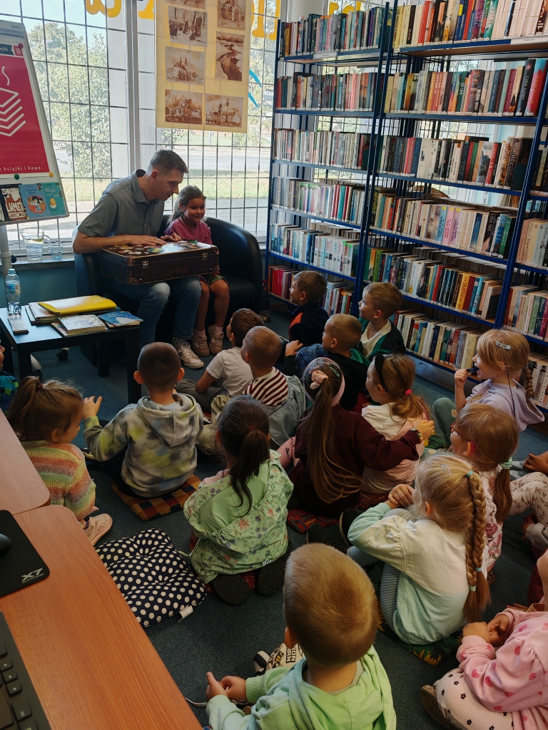 Spotkanie autorskie w bibliotece - dzieci uczestniczą w aktywnym czytaniu wiersza.